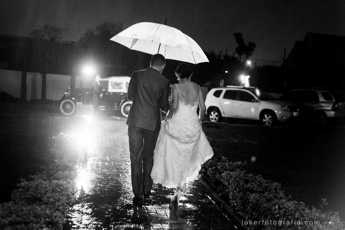 chuva no dia do casamento noivos saindo com guarda chuva