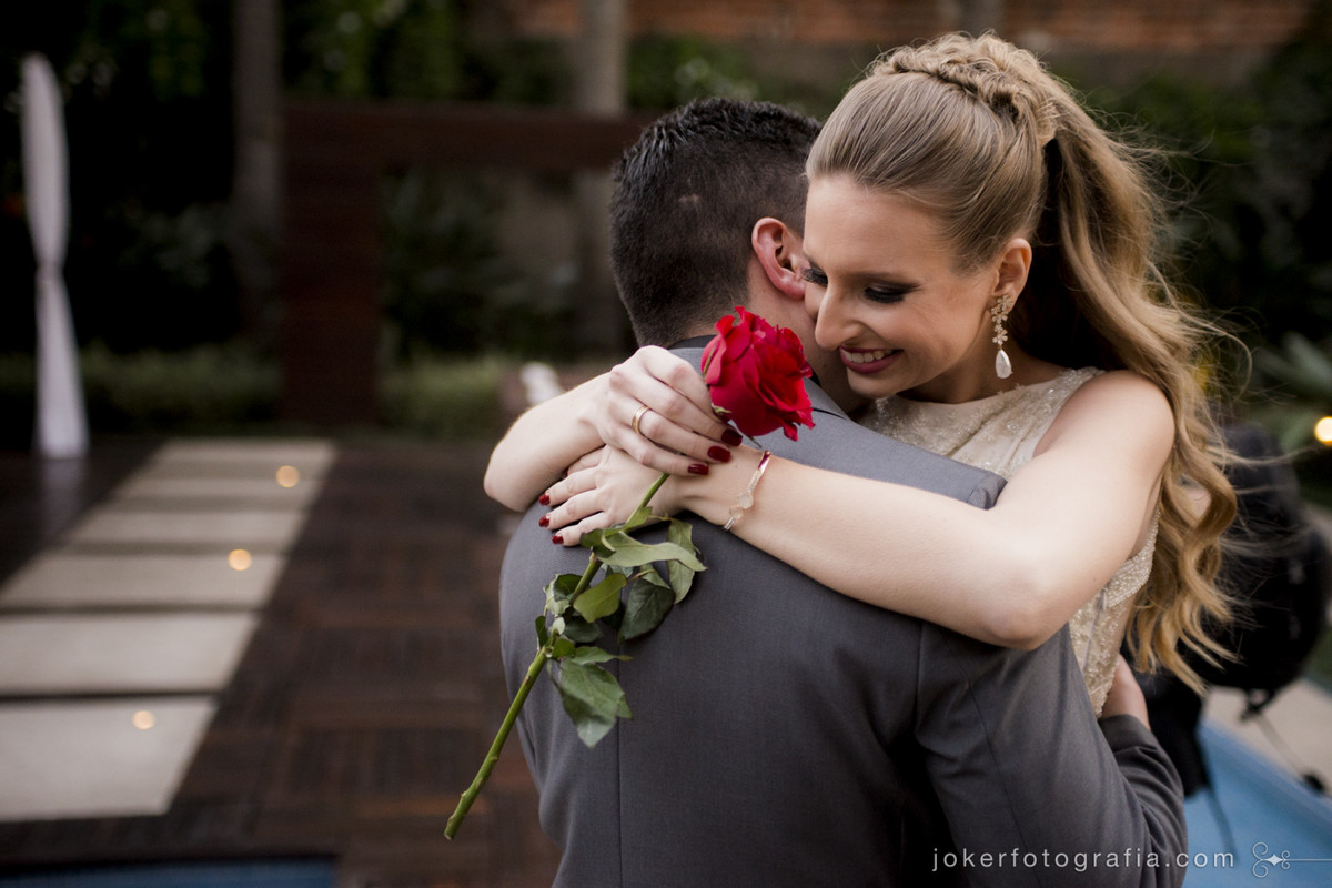 fotógrafo de casamento capta o primeiro abraço de noivos e ela segurando uma rosa