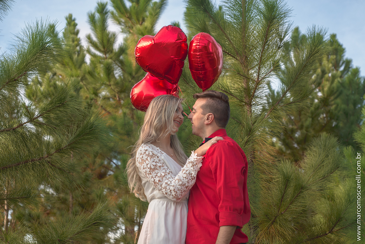 Casal de noivos em momento lindo com baloes vermelhos em forma de coração durante ensaio pré casamento. Pré wedding realizado no Las Acacias em Pelotas. Foto por Marco Moscarelli Fotografo