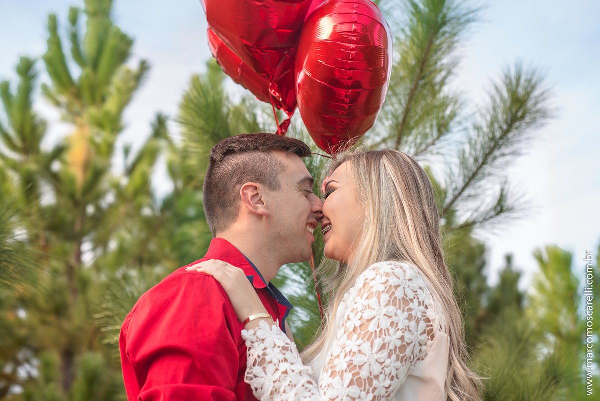 Casal de noivos em momento lindo com baloes vermelhos em forma de coração durante ensaio pré casamento. Pré wedding realizado no Las Acacias em Pelotas. Foto por Marco Moscarelli Fotografo