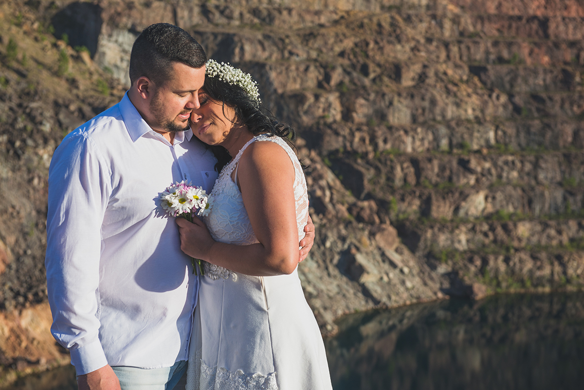Noivos posando para foto com o lago azul das minas do camaquã ao fundo durante ensaio de casalmento pré wedding
