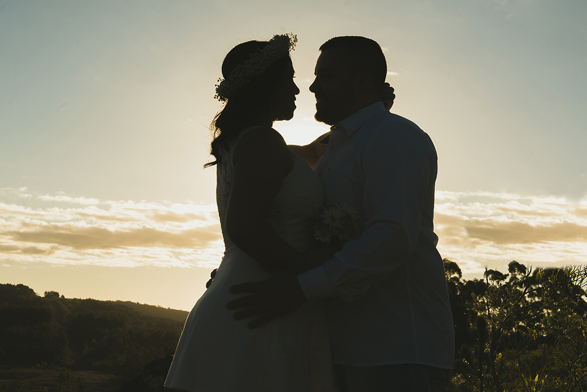 Linda foto contra a luz do casal de noivos em seu ensaio pré wedding realizado antes do casamento nas minas do camaquã