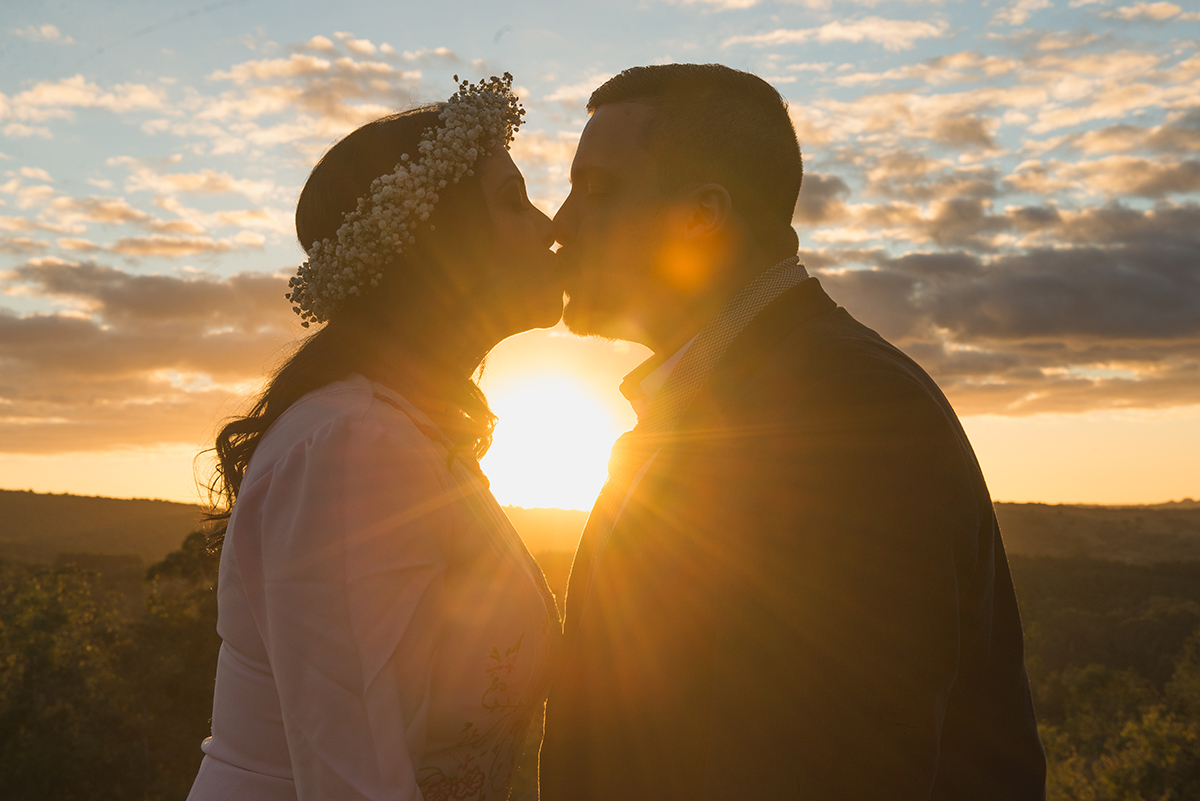 Foto do beijo dos noivos quase conra a luz do sol durante ensaio de casal.