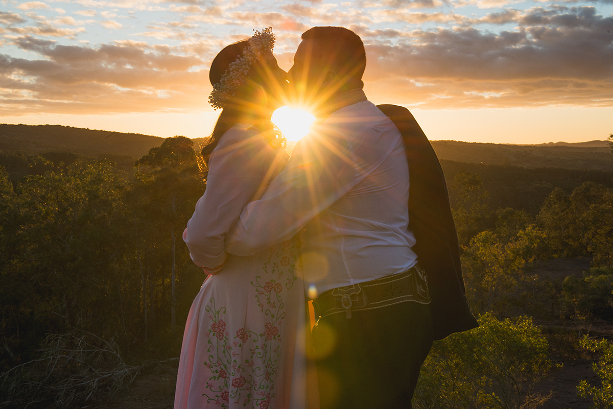 Foto do beijo dos noivos quase conra a luz do sol durante ensaio de casal.
