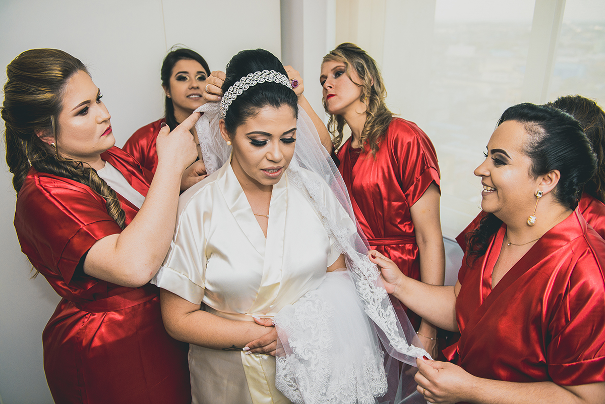 Madrinhas da noiva ajudando na colocação do vestido de noiva no dia do casamento durante o dia da noiva.