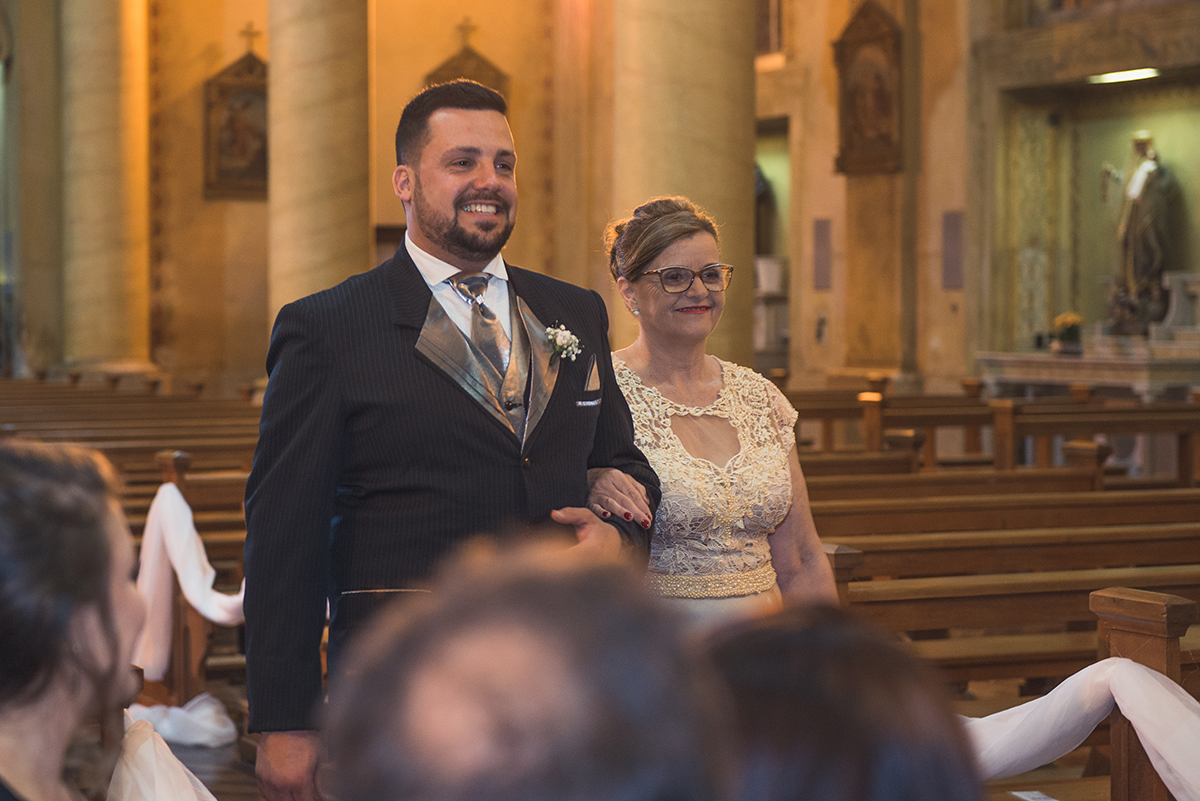 Noivo entrando na igreja com a sua mãe para a cerimonia de casamento.