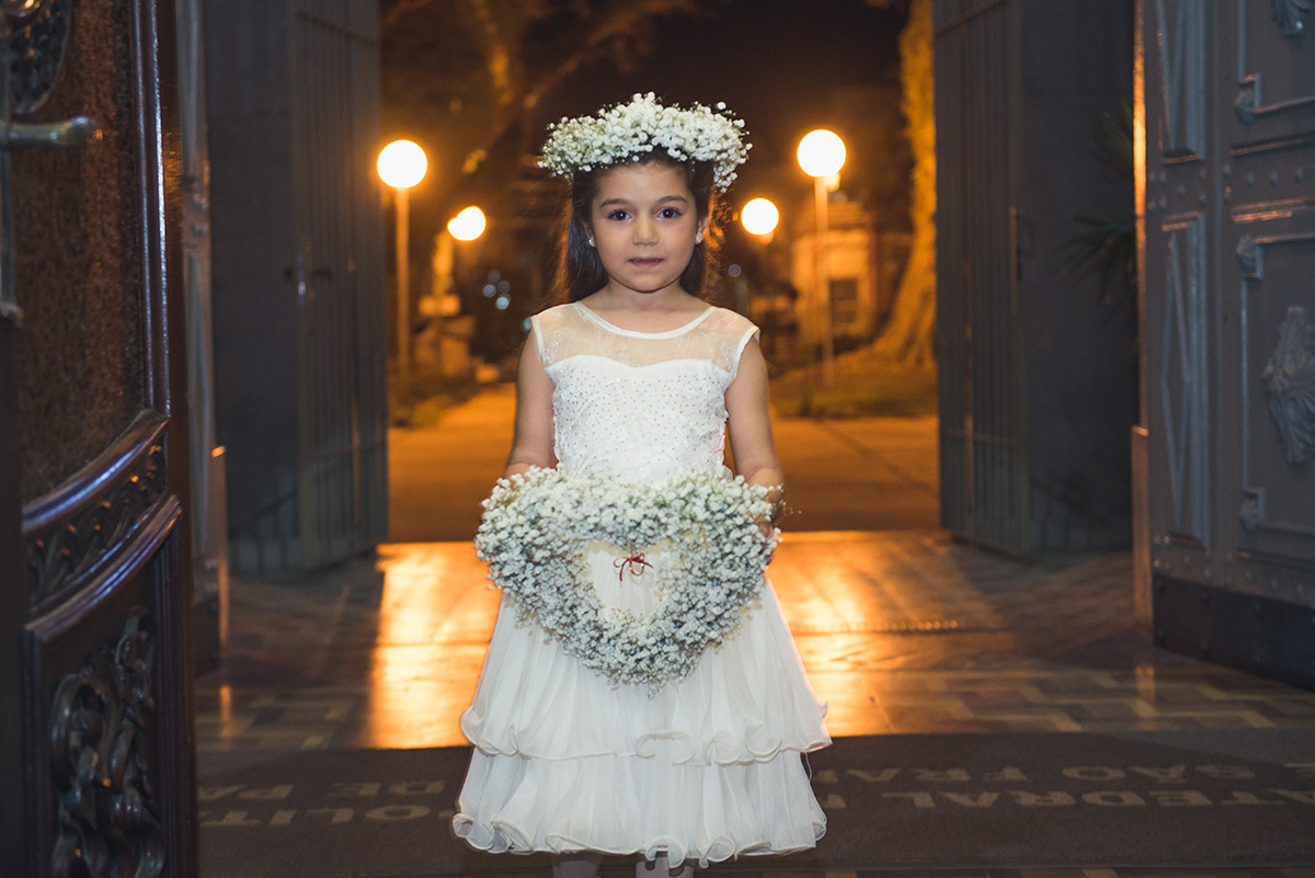 Aia entrando na igreja segurando um lindo arranjo de flores no dia do casamento.