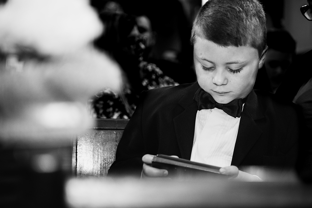 Detalhe durante o casamento do pequeno pagem brincando com o celular. Foto por Marco Moscarelli