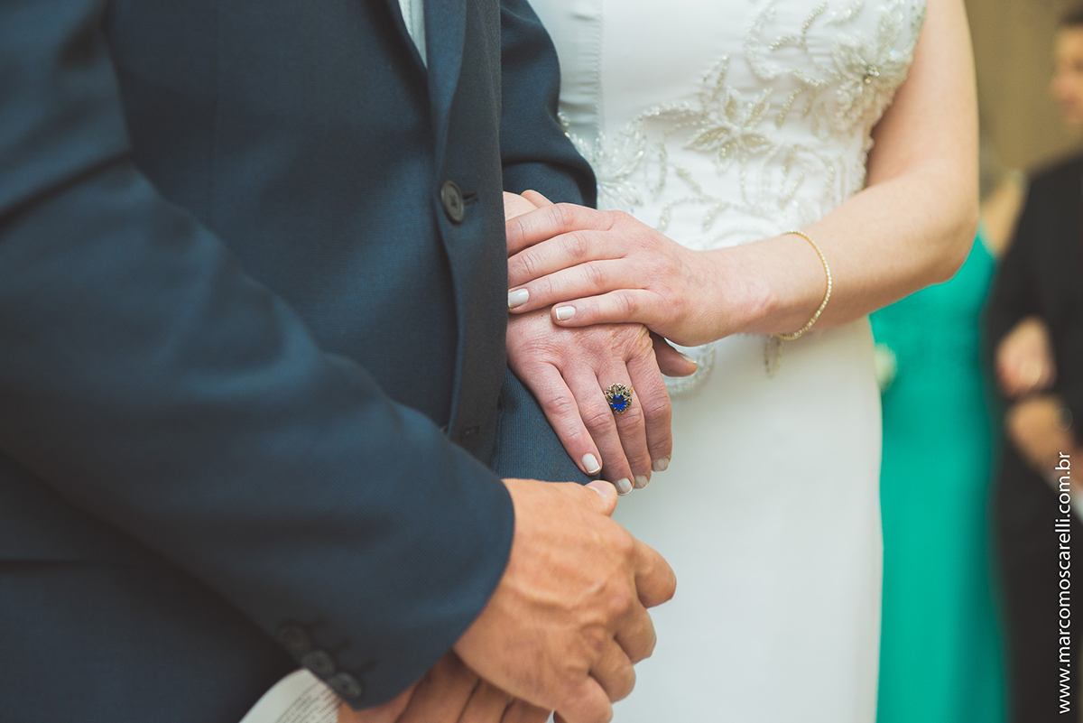 Detalhe da mão da noiva sobre a mão do noivo durante a ceromônia de casamento. Foto por Marco Moscarelli