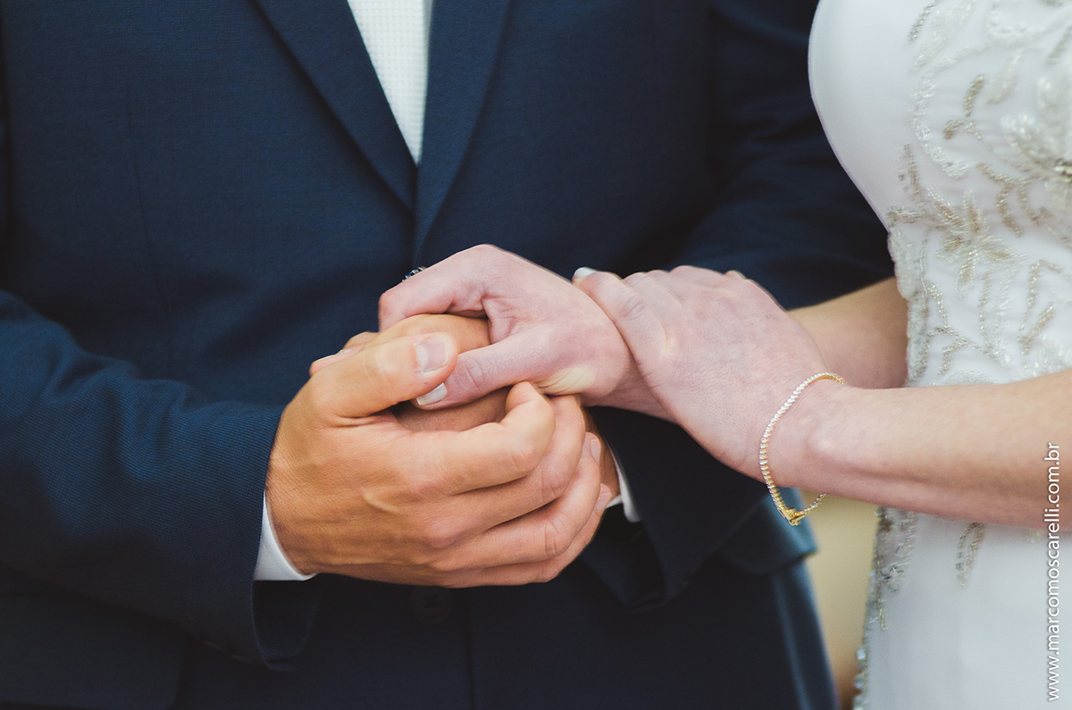 Detalhe das mãos dadas dos noivos durante a cerimônia de casamento. Foto por Marco Moscarelli