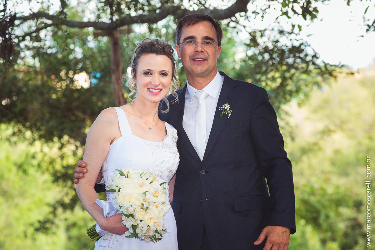 Noivos lindos e sorridentes em seu ensaioi após o casamento, posando ao pé de uma linda figueira. Foto por Marco Moscarell