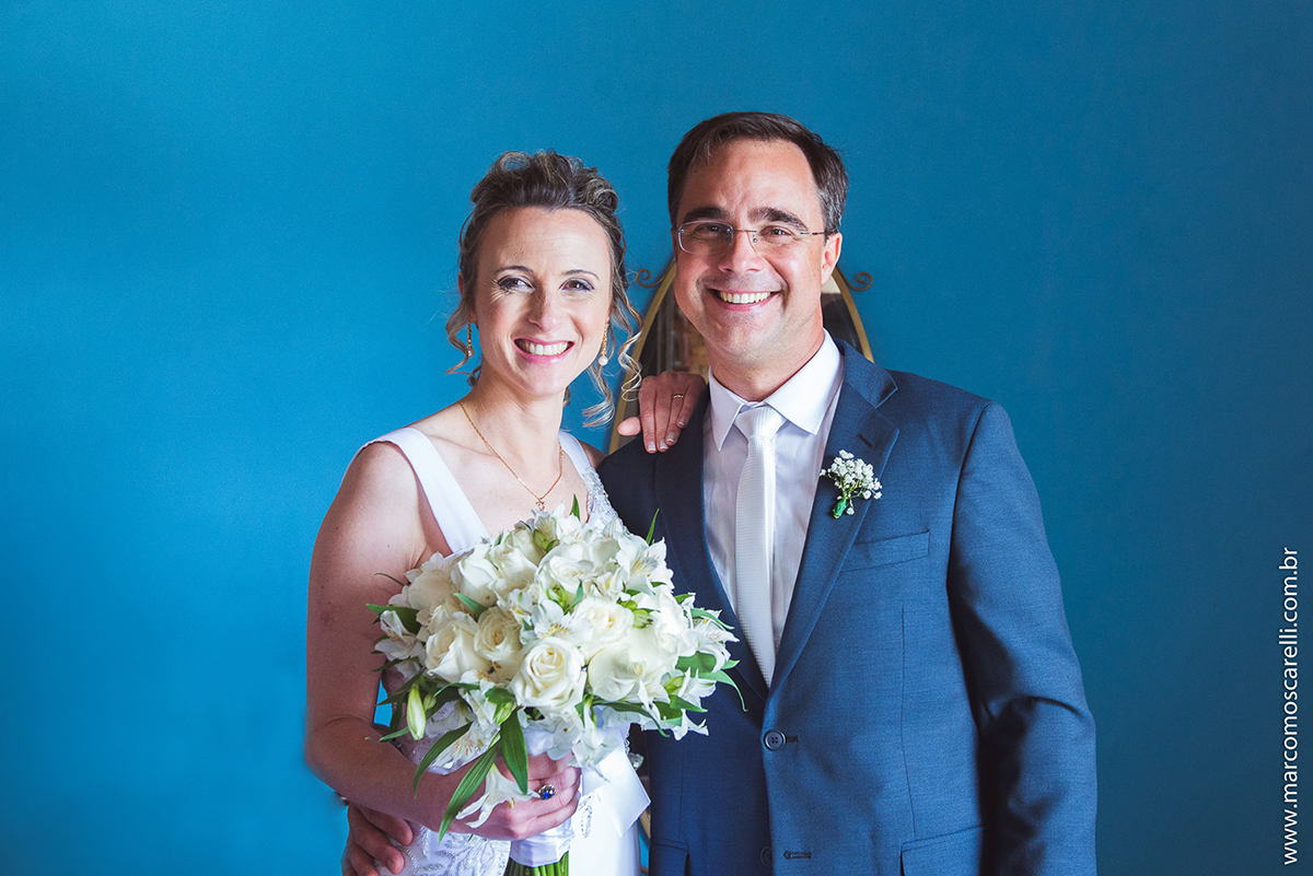 Casal de novos posando para o ensaio pós casamento em uma sala antiga com um lindo fundo azul. Foto por Marco Moscarelli
