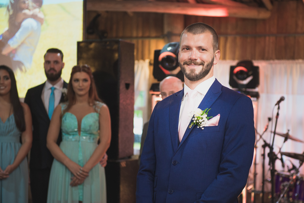 Noivo sorrindo ancioso a espera da noiva no altar. Foto Marco Moscarelli. Casamento Clube Caça e Pesca Pelotas