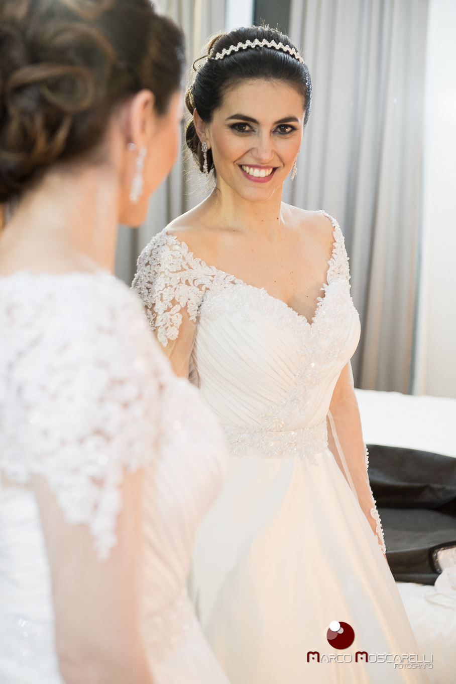Noiva admirando seu vestido de noiva no espelho antes da cerimonia de casamento. Foto por Marco Moscarelli