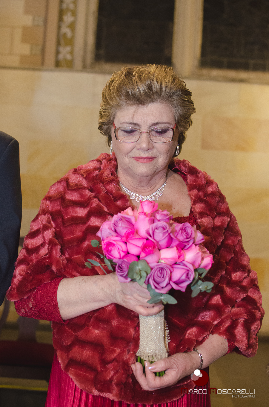 Mae da noiva emocionada com o buque na mão durante a celebração do casamento dos noivos. Foto por Marco Moscarelli