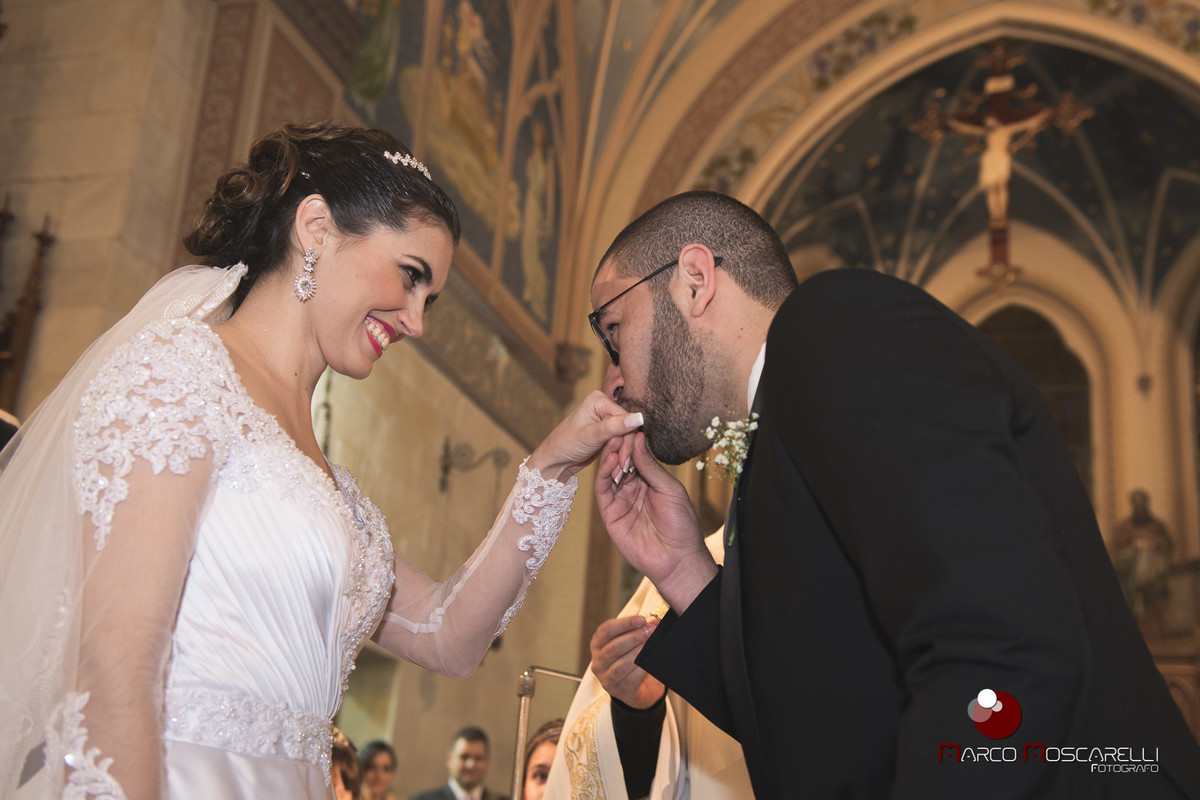 Noivo beja a mão da noiva na hora da troca de alianças de casamento. Foto por Marco Moscarelli