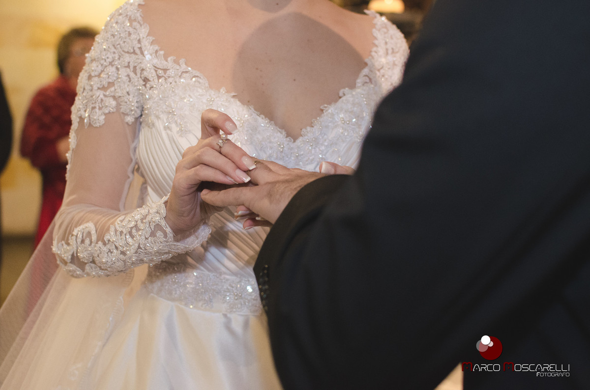 Linda noiva colocando a aliança de casamento no dedo do noivo na cerimonia de casamento