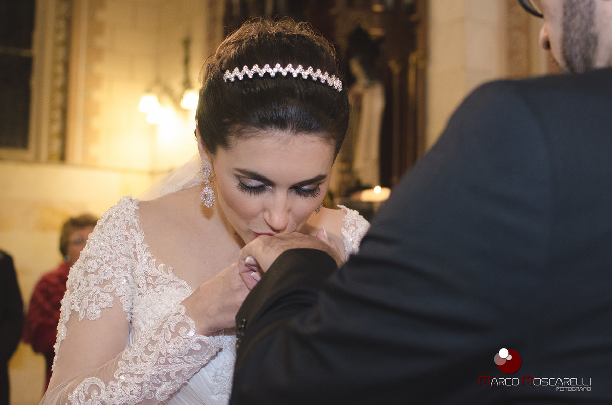 Noiva beijando a aliança do noivo durante a celebração do casamento. Foto por Marco Moscarelli