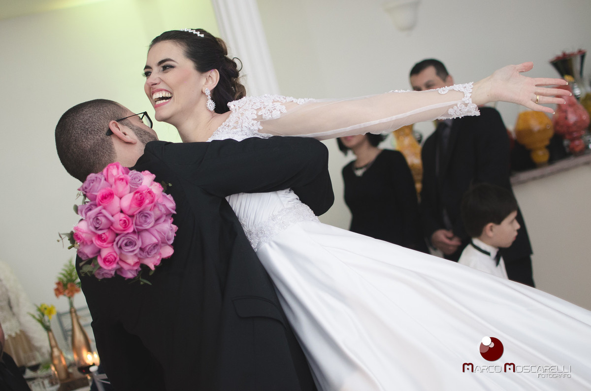 Noiva voando nos braços do noivo durante recepção de casamento.