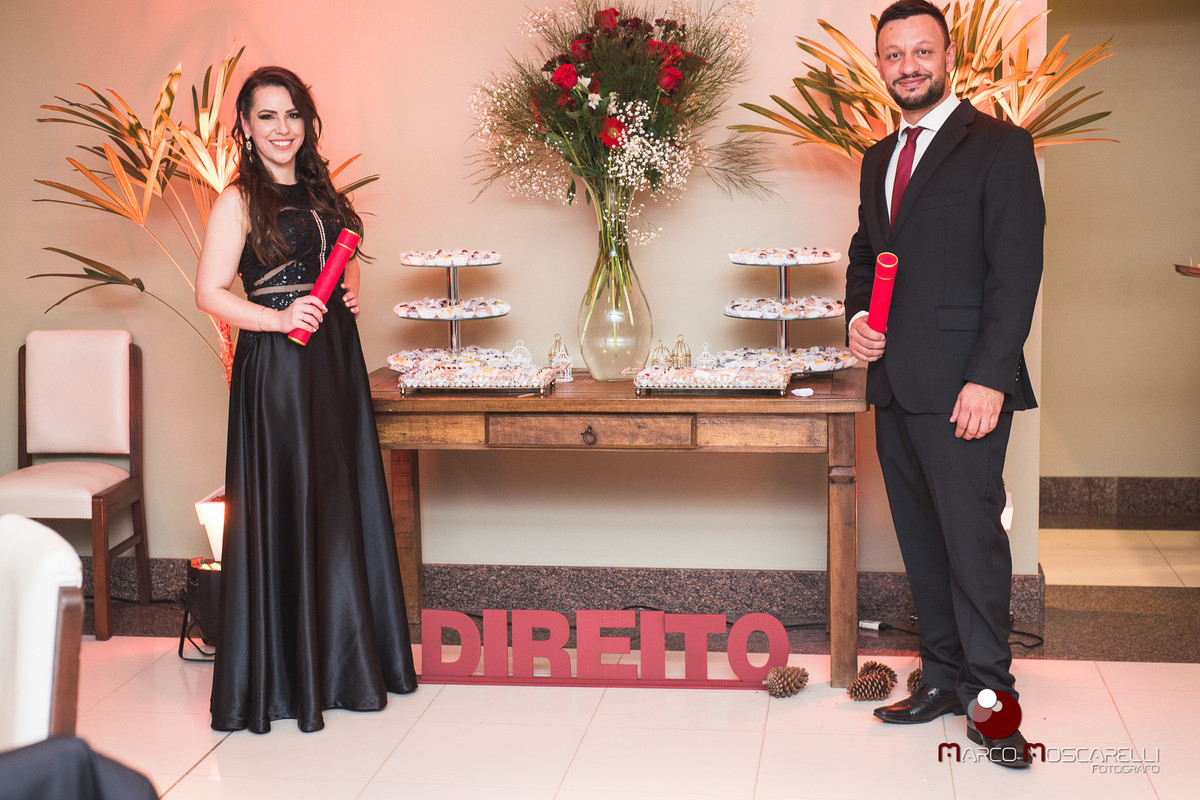 Formandos em direito posando a frente de mesa de decoração de formatura