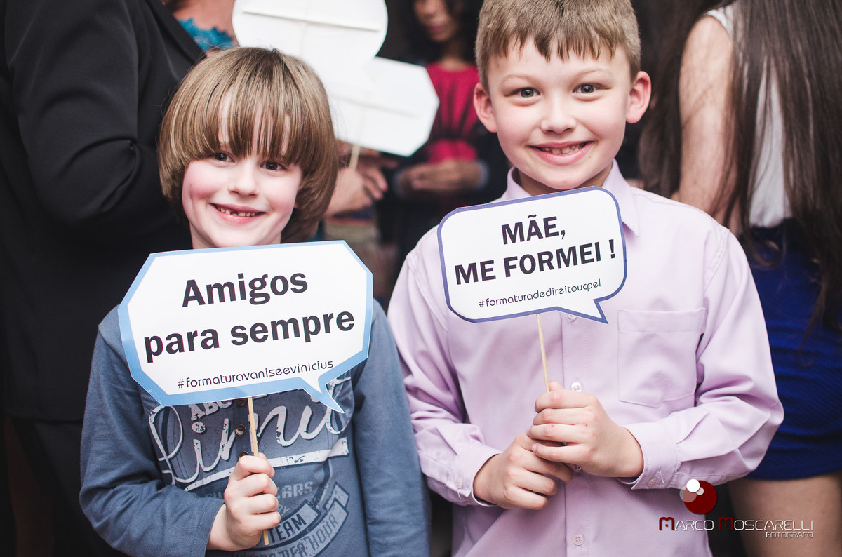 Crianças posando para foto com placas decorativas para o baile dos formandos. Foto por Marco Moscarelli