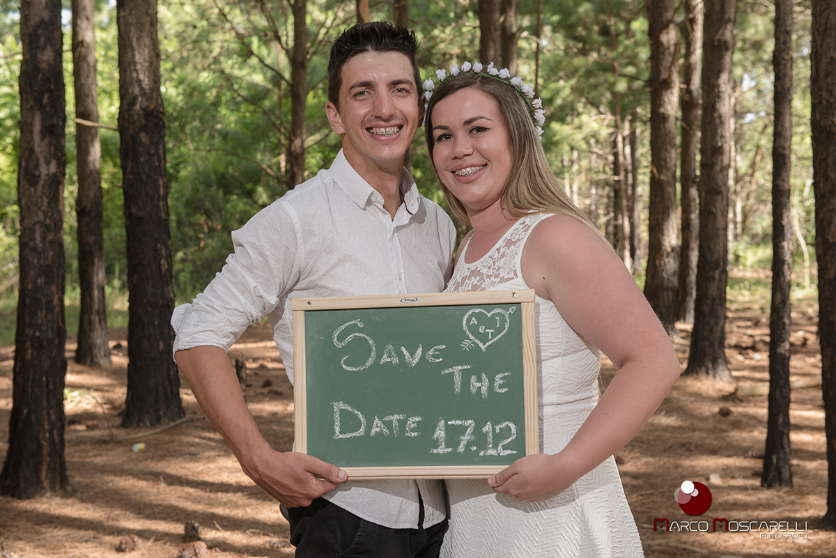 Noivos segurando quadro com o save the date do casamento durante ensaio pré wedding. Foto por Marco Moscarelli.