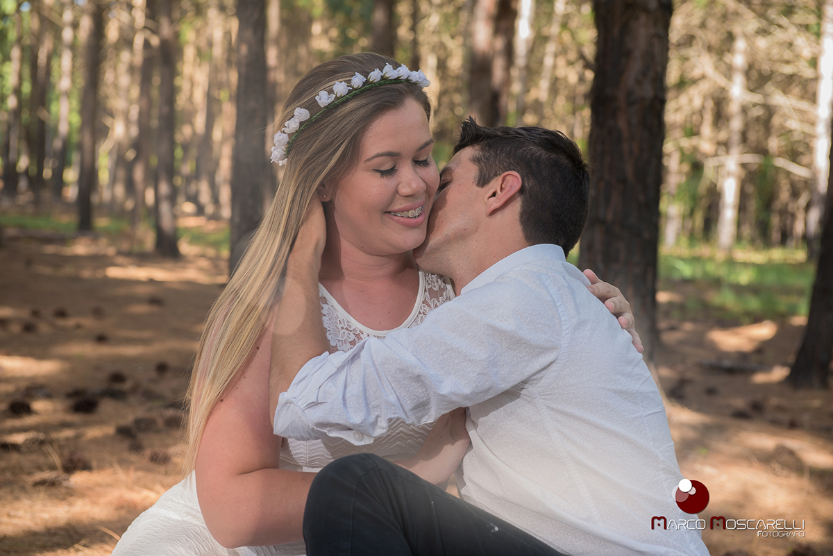 Noivo e noiva de rosto colado com lindo bosque de acacias ao fundo em ensaio pré-wedding. Foto por Marco Moscarelli