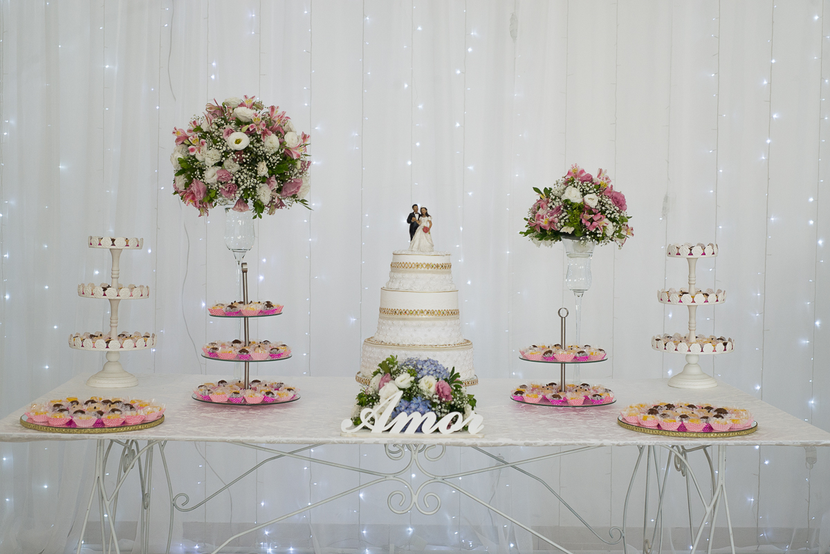 Foto da mesa do bolo dos noivos que compões a decoração da recepção de casamento
