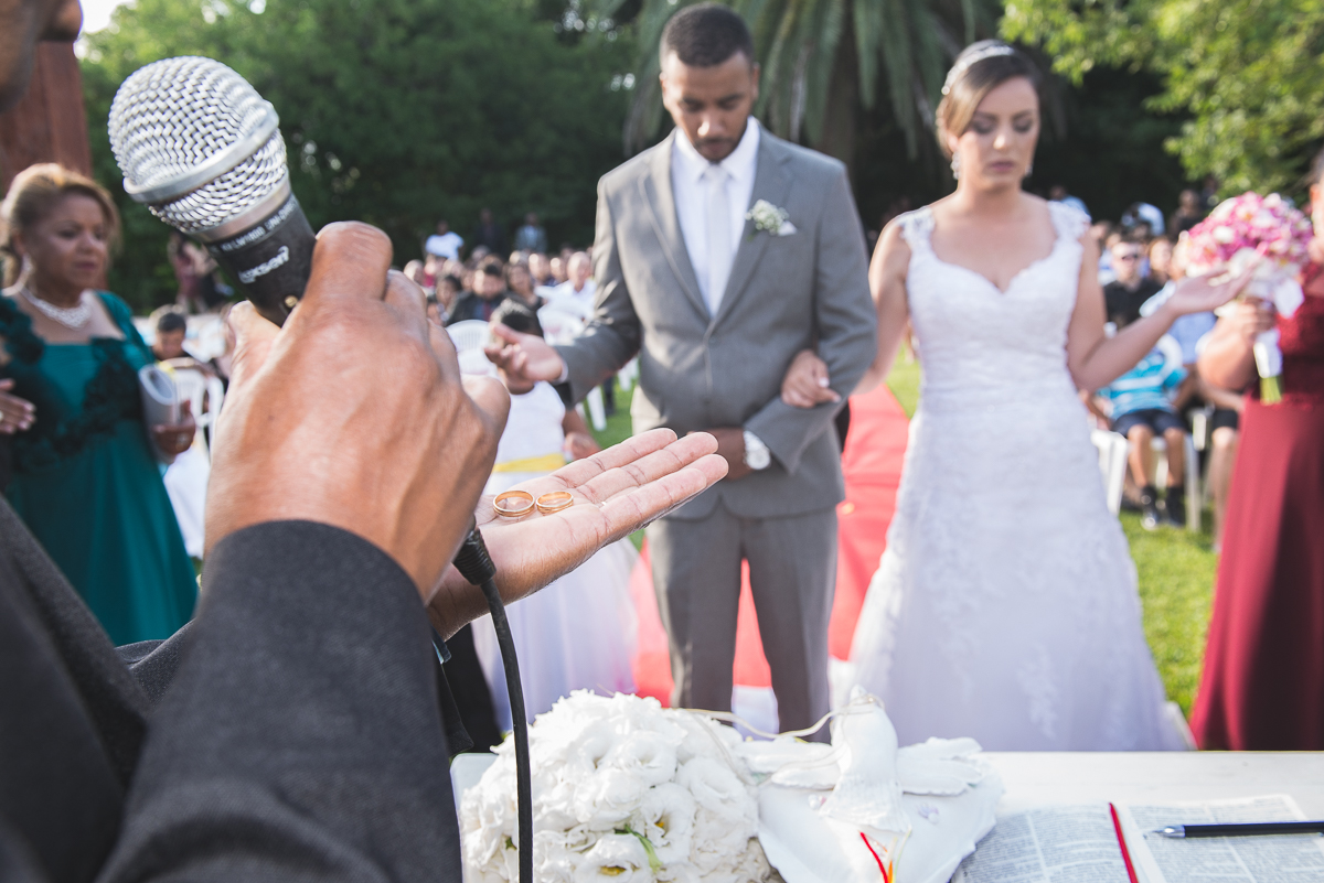 Padre abençoando as alianças dos noivos durante o casamento.