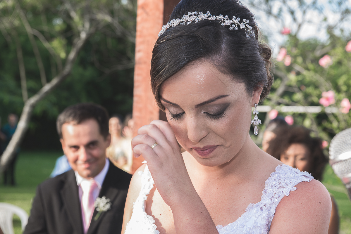Noiva enchugando uma lagrima no seu rosto durante a cerimônia de casamento.