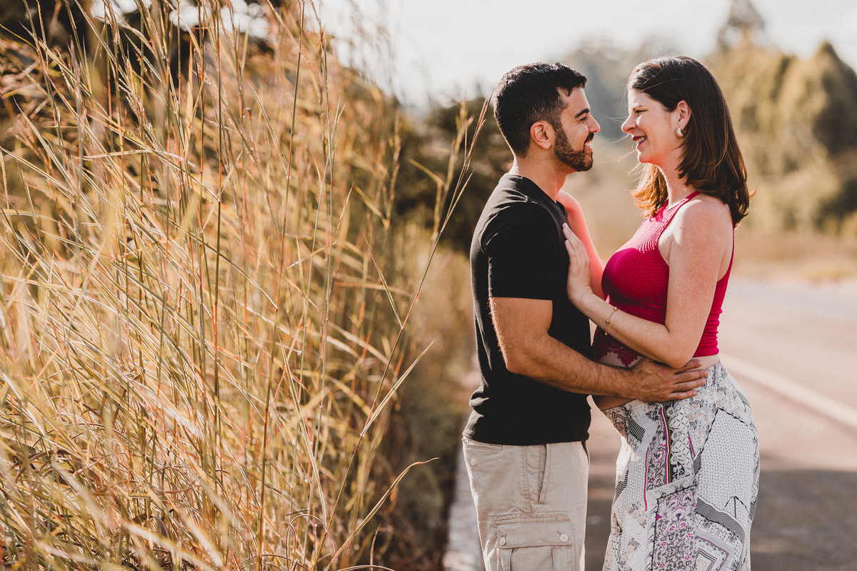 Ensaio de Gestante Ana Flávia e Guilherme. Casal abraçado sorrindo em estrada em Brasília. Foto feita pelo fotógrafo Gabriel Pelaquim.