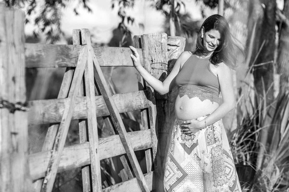 Ensaio de Gestante Ana Flávia e Guilherme. Mulher grávida em portão de fazenda em Brasília. Foto feita pelo fotógrafo Gabriel Pelaquim.
