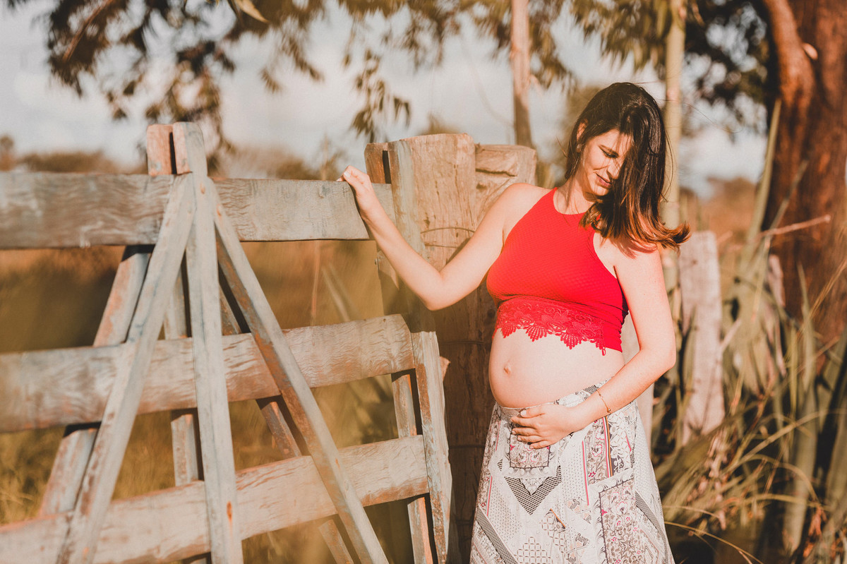 Ensaio de Gestante Ana Flávia e Guilherme. Mulher grávida em portão de fazenda em Brasília. Foto feita pelo fotógrafo Gabriel Pelaquim.