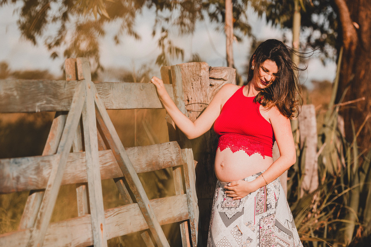 Ensaio de Gestante Ana Flávia e Guilherme. Mulher grávida em portão de fazenda em Brasília. Foto feita pelo fotógrafo Gabriel Pelaquim.
