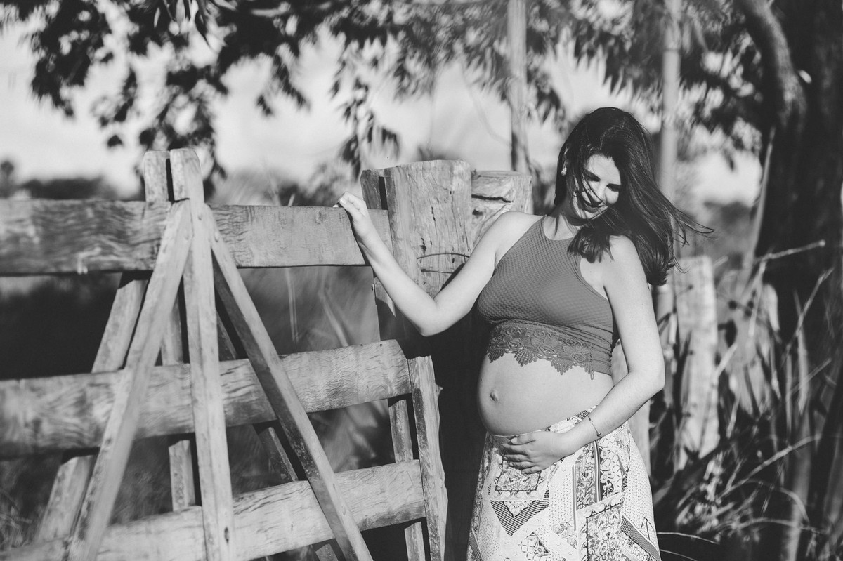 Ensaio de Gestante Ana Flávia e Guilherme. Mulher grávida em portão de fazenda em Brasília. Foto feita pelo fotógrafo Gabriel Pelaquim.