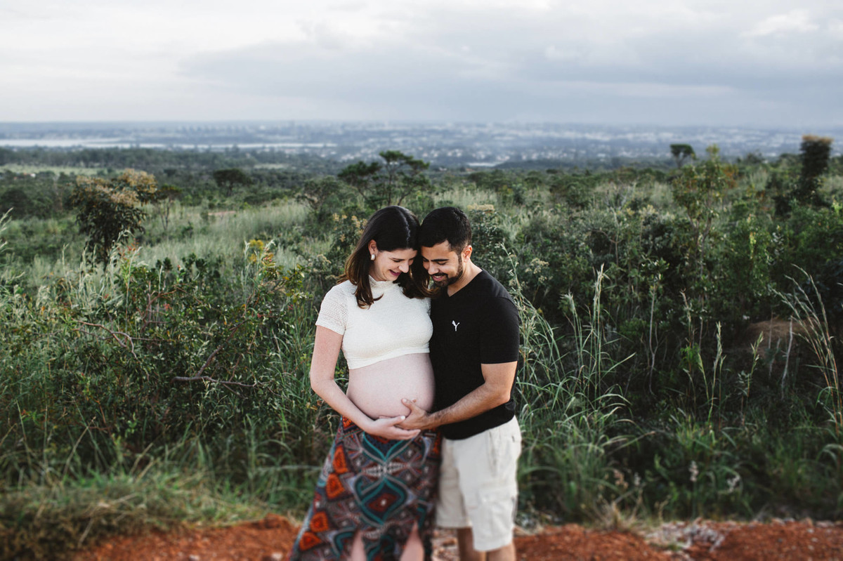 Ensaio de Gestante Ana Flávia e Guilherme. Casal abraçado sorrindo no mato em Brasília. Foto feita pelo fotógrafo Gabriel Pelaquim.