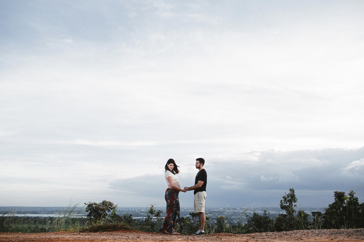 Ensaio de Gestante Ana Flávia e Guilherme. Casal de mãos dadas no mato em Brasília. Foto feita pelo fotógrafo Gabriel Pelaquim.