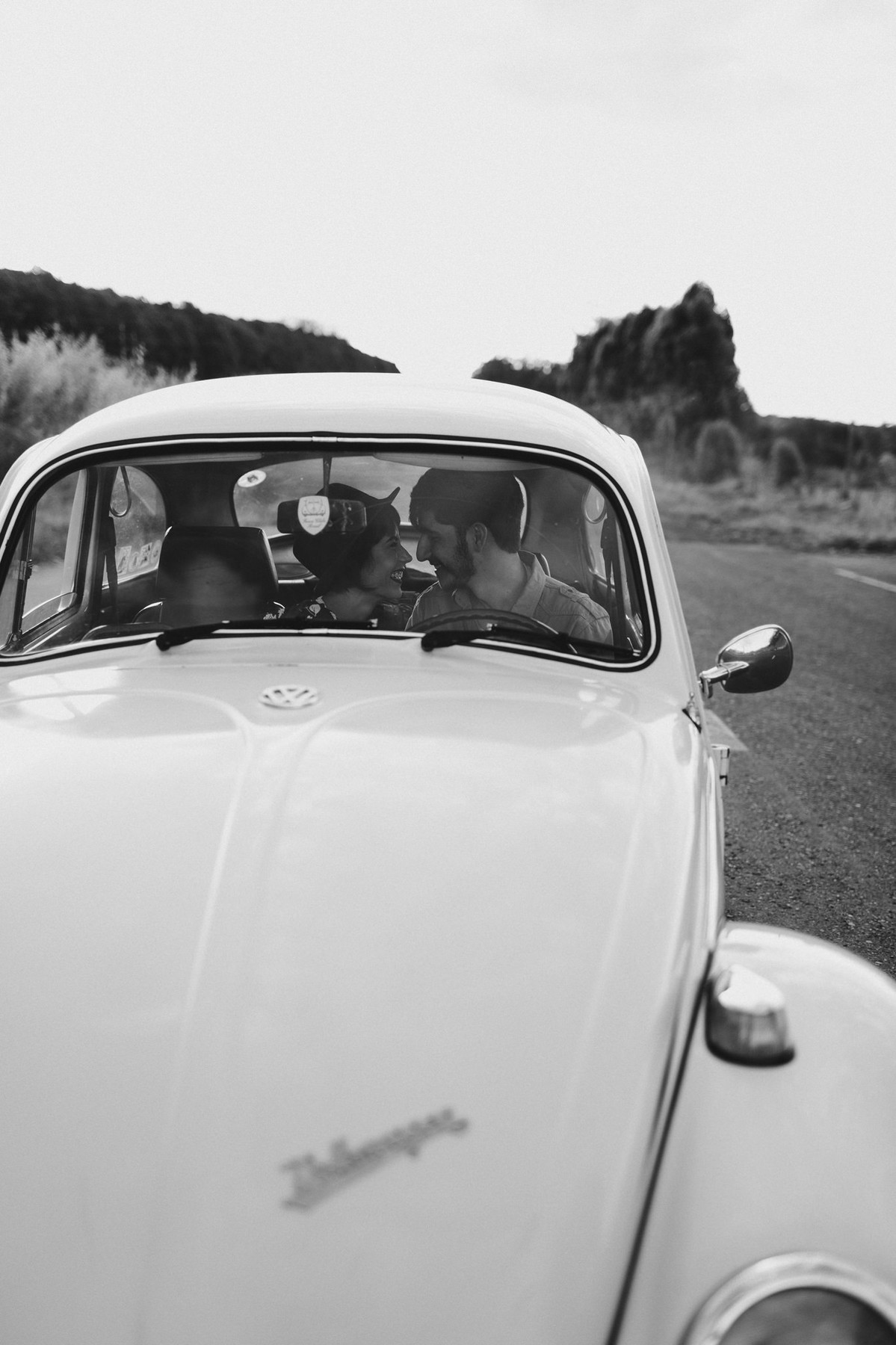 Casal sorrindo dentro de fusca em Brasília. Foto feita pelo fotógrafo de casamento Gabriel Pelaquim.