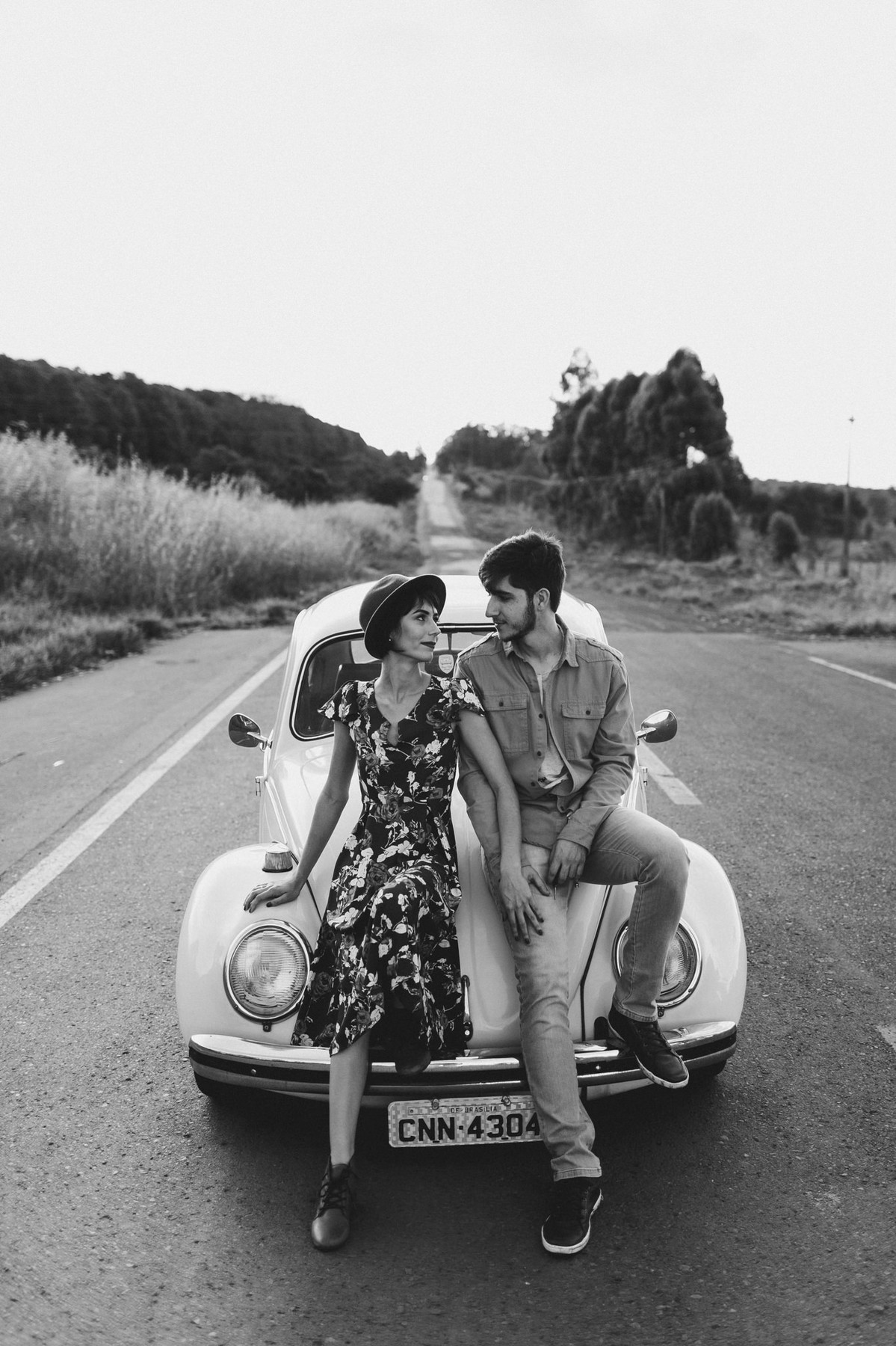 Casal sentado no capô de fusca em estrada em Brasília. Foto feita pelo fotógrafo de casamento Gabriel Pelaquim.