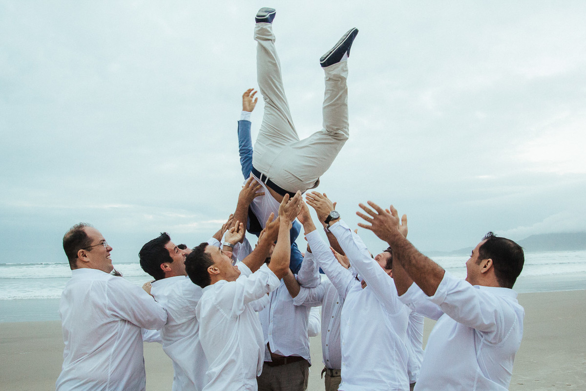 PADRINHOS JOGANDO O NOIVO PARA O ALTO FOTOGRAFIA DE CASAMENTO CARLA E RAFAEL EM UBATUBA SP