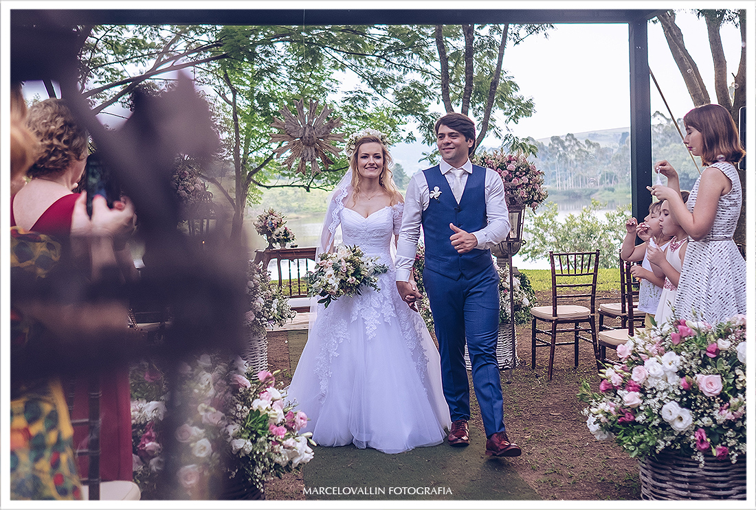 Foto da saída dos noivos na cerimonia casamento no campo