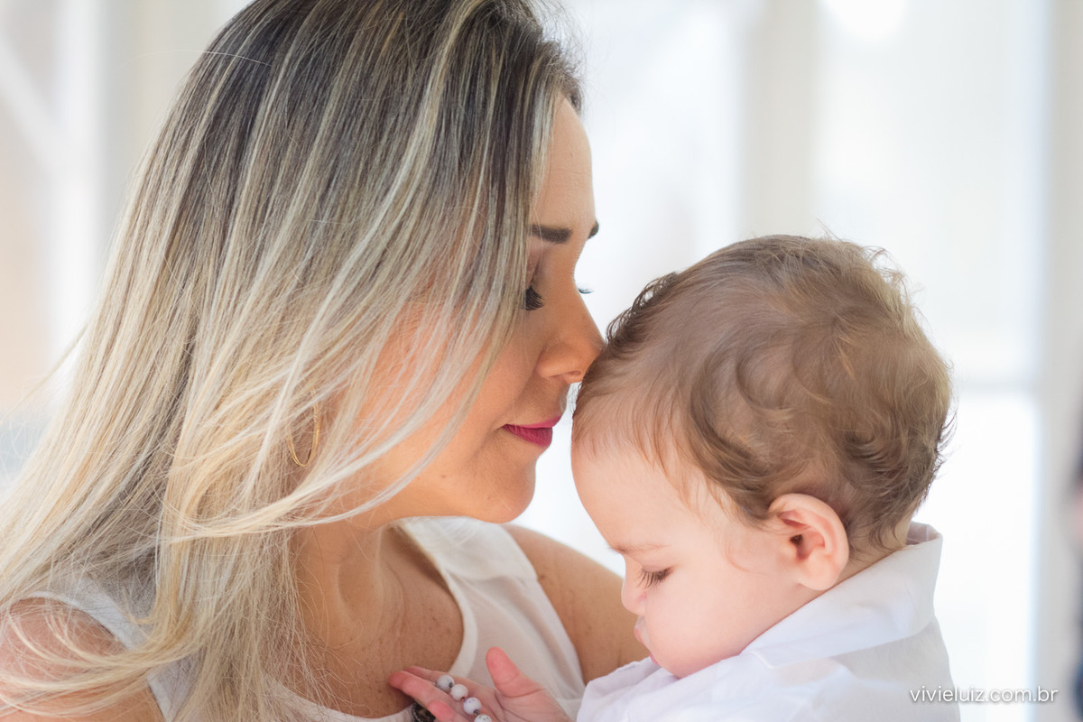 Criança no colo da mãe no batizado fotografado por Vivi e Luiz Fotografias