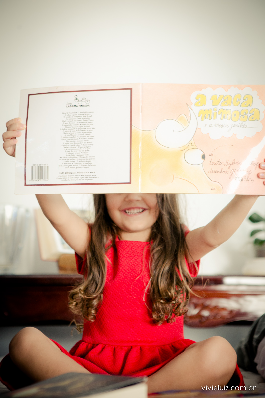 Menina levantando o livro e sorrindo