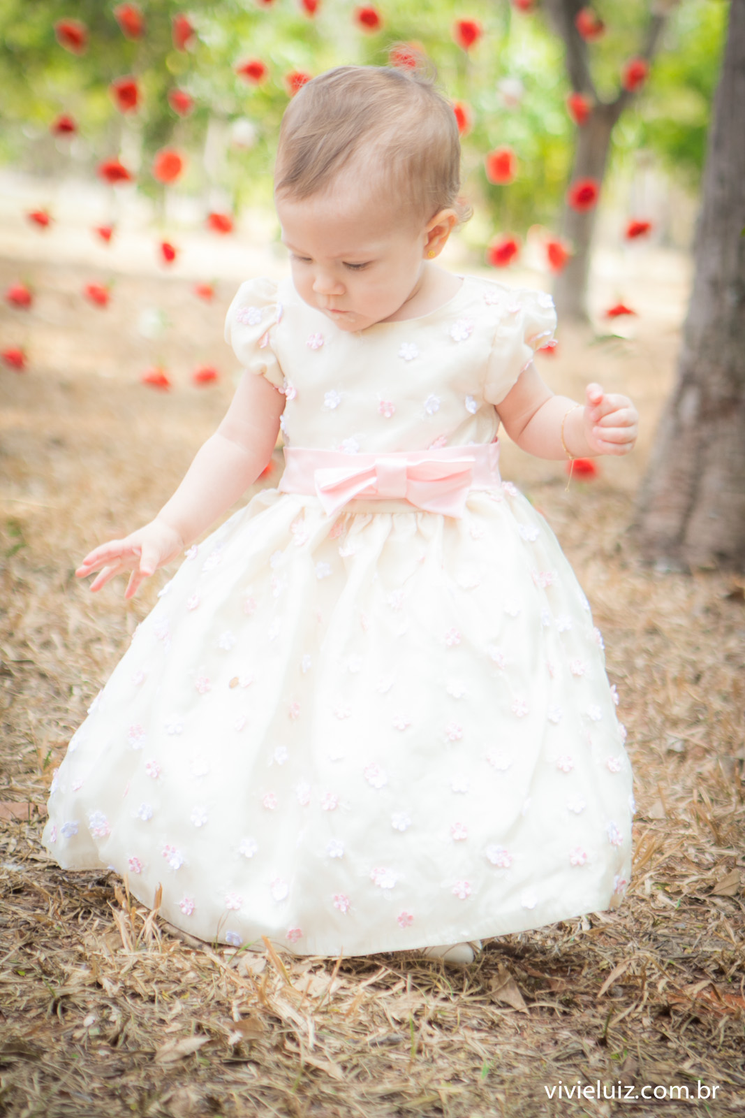 criança com vestido branco e flores ao fundo