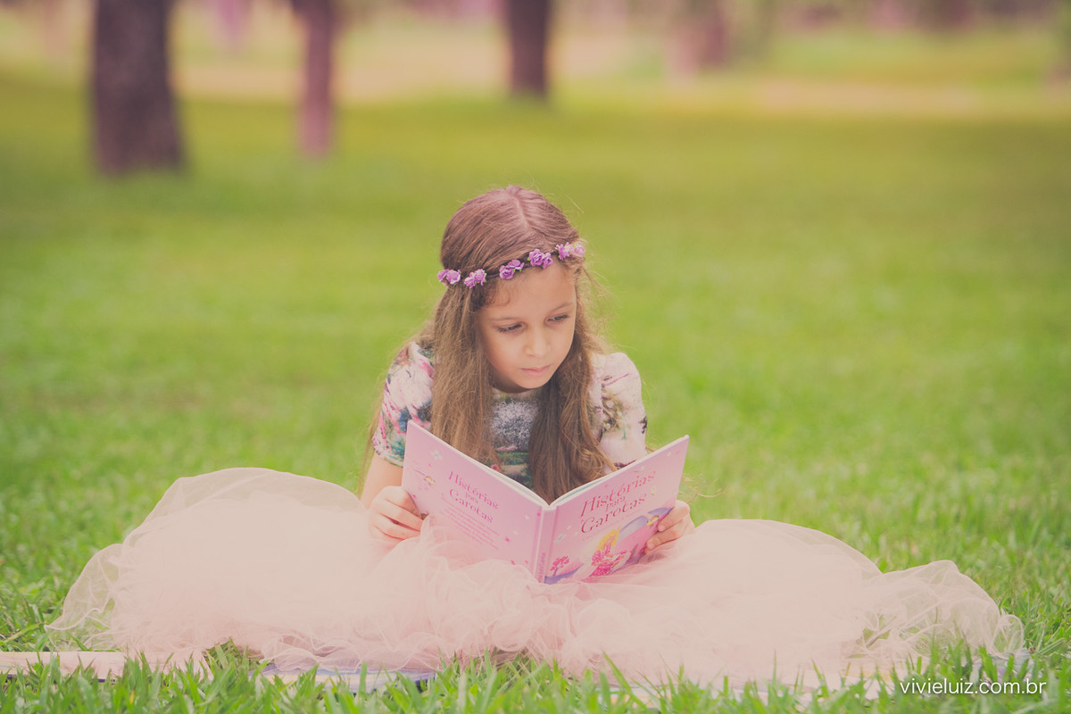 menina lendo livro no campo verde