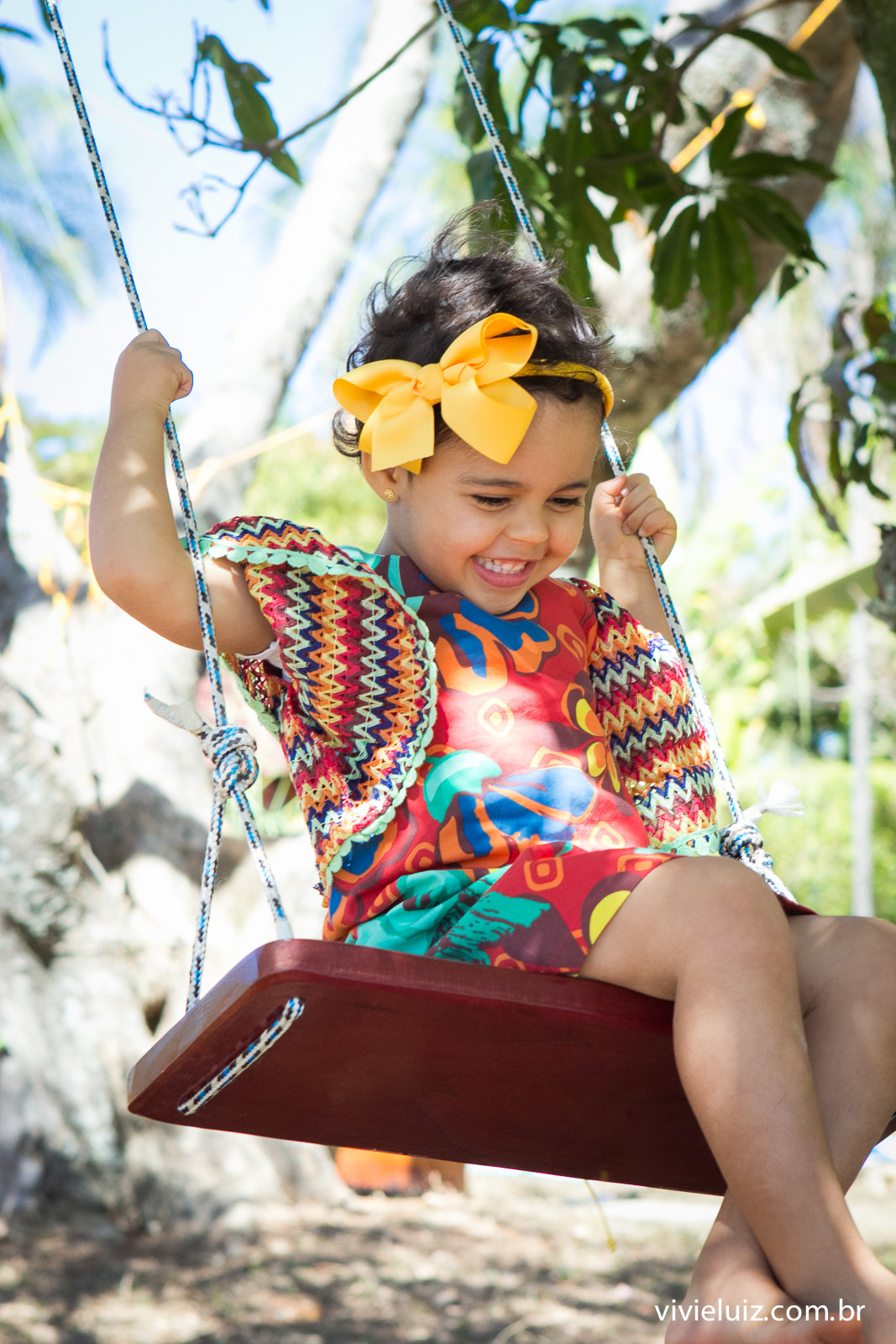menina com roupa colorida no balanço de arvore