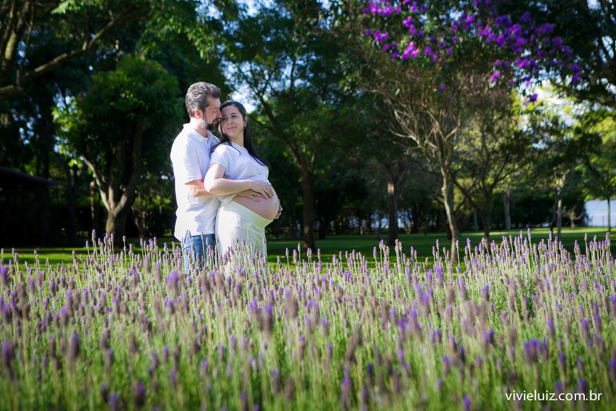 pai abraçando a mão atrás num lindo campo registrado pelo fotógrafo de gestante Brasília DF vivi e luiz num lindo dia
