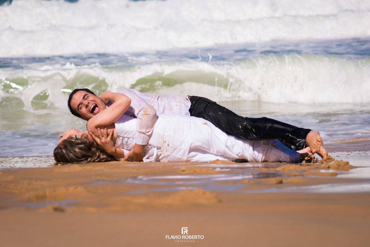 noiva rolando com o noivo na areia da praia