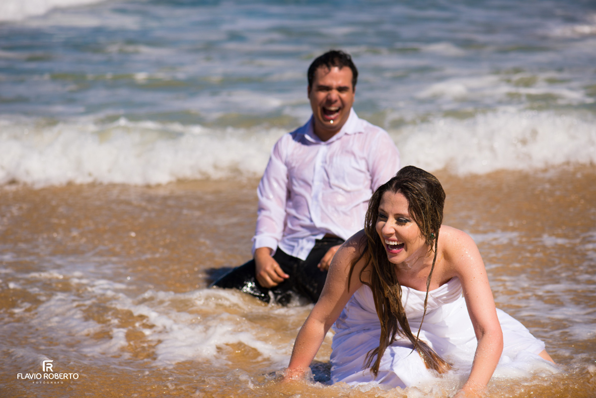 noivos rindo no trash the dress na praia