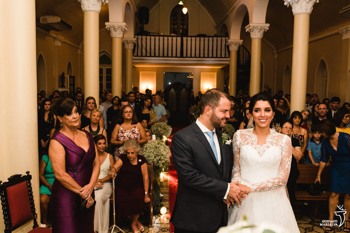 Novo fazendo carinho na noiva e sendo observado pela mãe durante a cerimônia de casamento